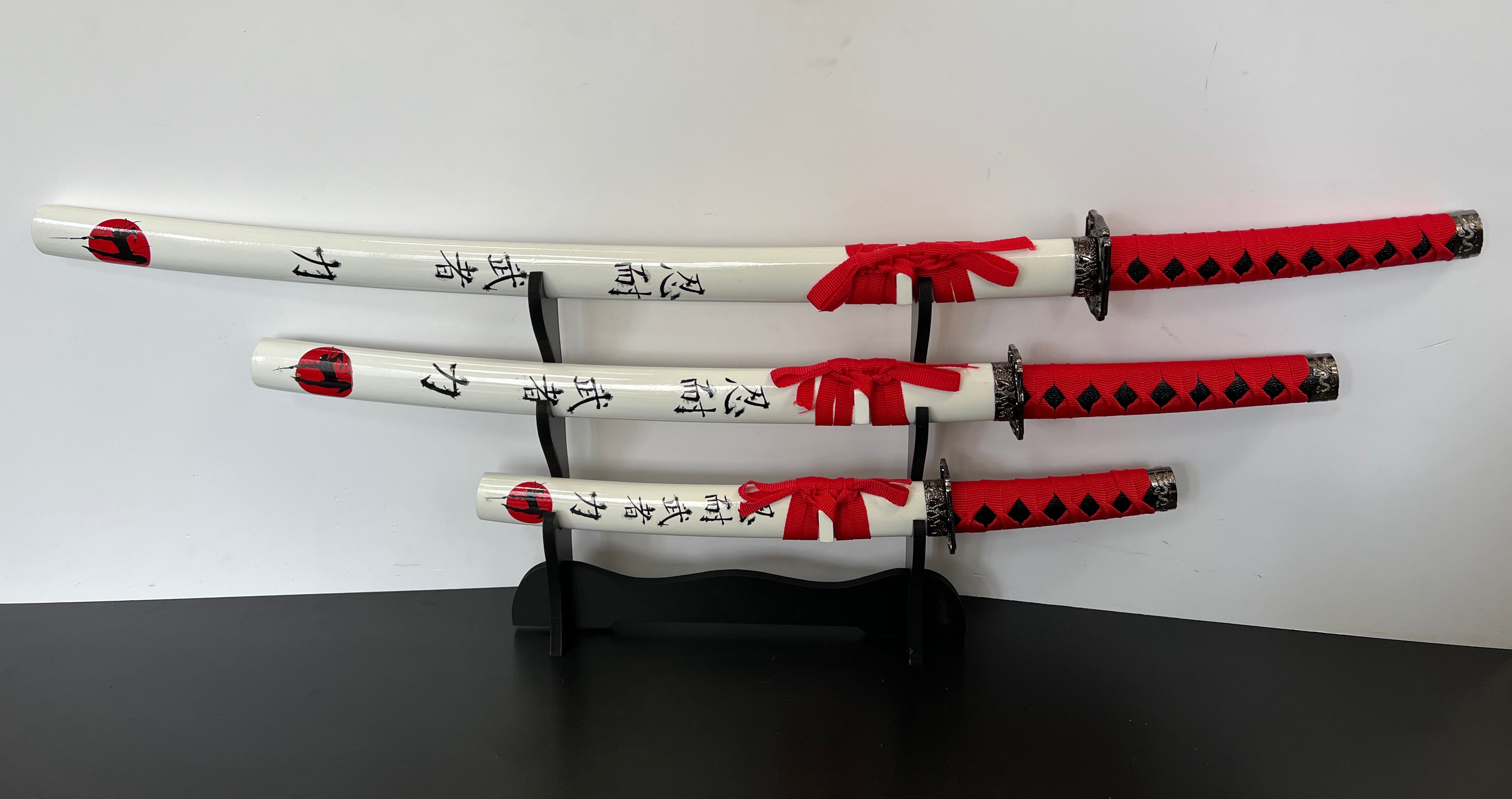 Eine 4- Teilige Samuraigarnitur, welche aus einer Katana, einem Wakizashi und einem Tanto besteht. Alle Schwerter haben das selbe Design und sind aufeinander sehr gut abgestimmt. Auf der Schwertscheide sind Japanische Schriftzüge und ein Ninja. Die Tsuba haben eine Eckige From welches bei Katanas außergewöhnlich ist, dennoch sehr gut aussieht. Außerdem befindet sich eine Schwerthalterung im Lieferumfang, welche platz für alle 3 Schwerter bietet.